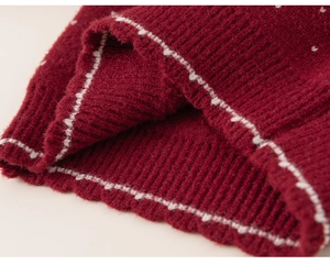 Detailed close-up of dark red ribbed knit fabric with white decorative stitching accents