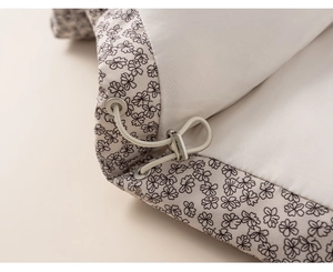 Detail of floral toddler coat featuring an adjustable cream drawstring and silver eyelet