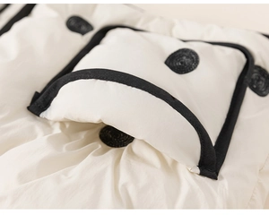 Detail of white quilted fabric on a winter jacket with black piping and round patch detail