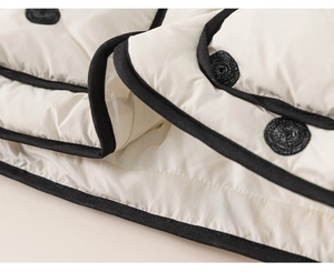 Close-up of quilted cream toddler jacket featuring black trim and textured buttons