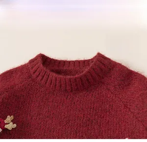 Detail of red knit sweater with ribbed neckline and golden elk antler embroidery