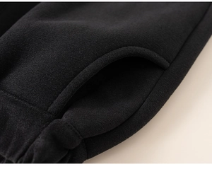 Macro shot of black thermal fleece pants showing elastic waist and durable pocket stitching