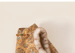 Detailed view of golden brocade fabric with fur trim and traditional button on the dress