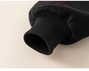 Detail of black ribbed cuffs on a thick cotton sweatshirt with red embroidery accents
