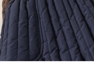 Macro view of navy blue vertical quilting and brown trim detail on kids winter coat