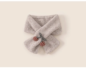 Close-up of oatmeal knitted children's scarf with a cute cherry detail for winter warmth