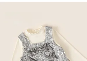 Detail of sequined girls dress featuring a large velvet bow and ruffled neckline