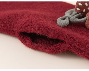 Detailed close-up of dark red knitted fabric featuring a cute strawberry and bow
