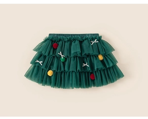 Detail of dark green tiered mesh tutu skirt with festive pom-poms and bow for girls