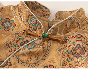 Macro shot of traditional Chinese high collar with golden crane brocade and green bead clasp