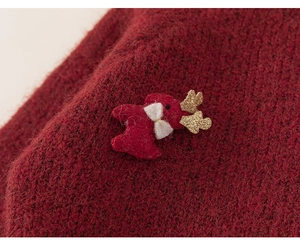 Macro detail of knit red sweater featuring festive 3D felt deer with gold sequins