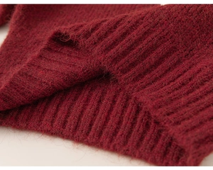 Macro detail of dark red knit sweater showing fluffy wool texture and ribbed cuffs