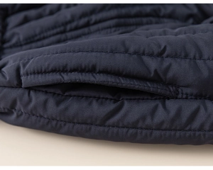 Close-up of high-quality stitching and quilted texture on dark blue padded winter jacket