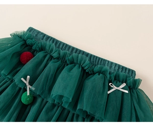 Detailed view of dark green tutu skirt with festive red pom-poms and silver bows