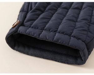 Detailed macro view of dark blue quilted sleeve with vintage brown button and neat stitching