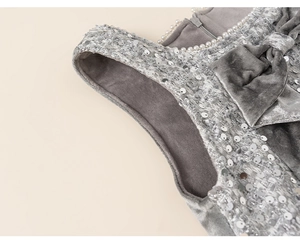 Detail eines grauen Samtkleides für Mädchen mit silbernen Pailletten und Perlenhalsband