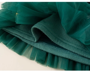 Detail shot of green festive sweater showing the layered tulle and thick ribbed knit texture