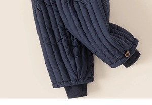 Detail of navy quilted thermal trousers for kids with ribbed cuffs and wooden button