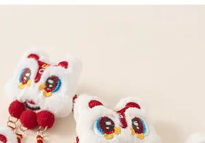 Détail de pinces à cheveux lion chinois rouge avec pompons en fourrure et broderie