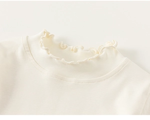 Detail of cream knit sweater showing delicate ruffle edge collar and cotton texture