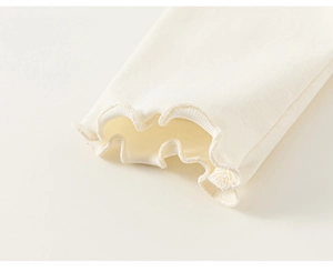 Detail of ruffled cuffs on cream ribbed knit sweater for girls with fine stitching