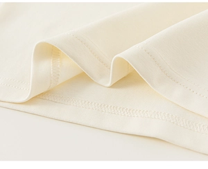 Close-up of cream knit dress hem with professional double-needle stitching detail