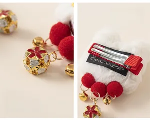 Détail de pinces à cheveux à pompons rouges et cloches dorées pour petites filles