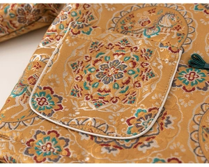 Detail of yellow brocade fabric featuring traditional floral patterns and green frog button