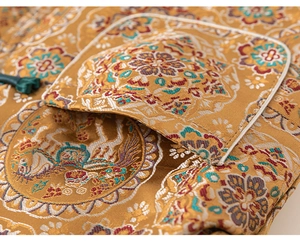 Close-up of golden brocade fabric with crane embroidery and traditional knot button