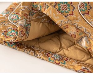 Detail of traditional Chinese gold brocade fabric with warm floral embroidery and quilting