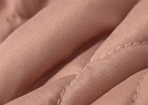 Detailed macro view of pink quilted fabric texture with premium stitching and soft padding