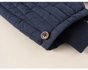 Detail of dark blue quilted coat with ribbed windproof cuffs and decorative wood buttons