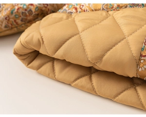 Detail of golden quilted fabric with ethnic print trim and diamond stitch pattern