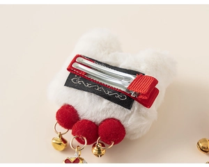 Détail montrant des pompons rouges, clochettes dorées et ruban antidérapant sur la barrette