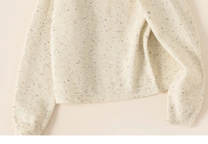 Detail of soft cream knit sweater with colorful nep yarn and ribbed hem and cuffs