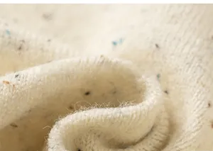Macro detail of off-white knit fabric with colorful flecks and soft winter texture