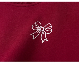Détail d'un sweat bordeaux avec imprimé nœud blanc et texture du col côtelé en polaire