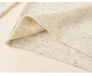 Detailed close-up of thick speckled knit fabric hem on a warm winter girls sweater