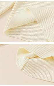 Detailed macro view of the ribbed knit hem on a cream plush toddler winter dress