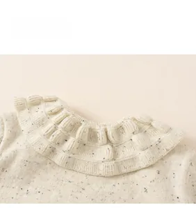 Detail of girls' cream knit sweater with colorful flecks and ruffled collar design