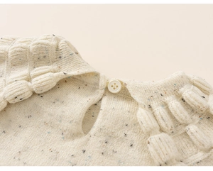 Close-up of white knitted sweater featuring colorful speckles and textured bubble knit collar