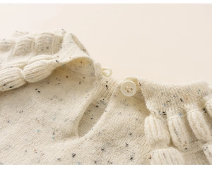 Detail of beige knit sweater with colorful speckles and back button closure
