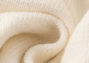 Nahaufnahme von weichem cremeweißem Strickstoff mit hochwertigen Textilfaserdetails