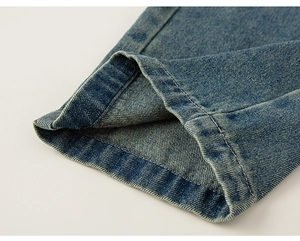 Detail of dark blue denim trousers featuring premium stitching and washed texture