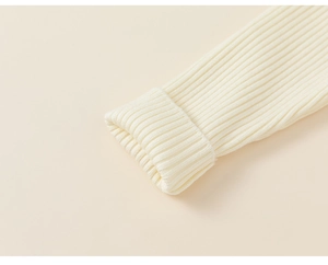 Detailed macro view of the warm white ribbed knit cuffs and fine stitching on the kids top