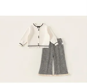 Detail von Mädchen Strickjacke mit Herzknöpfen und gestreifter Hose mit Fransen