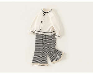 Details des weißen Strick-Cardigans mit Herzknöpfen und gestreifter Hose für Mädchen
