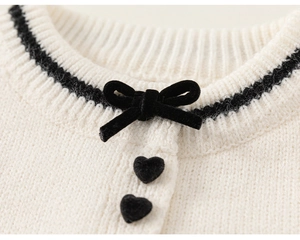 Detail der Strickjacke mit Samtschleife und schwarzen beflockten Herzknöpfen