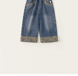 Détail d'un pantalon large en denim bleu avec des accents léopard sur les poches et le bas