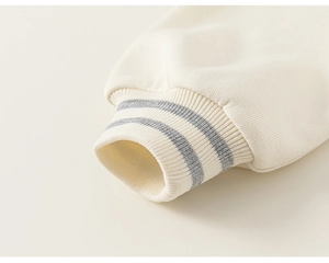Détail des poignets côtelés avec rayures grises sur le cardigan crème pour enfants